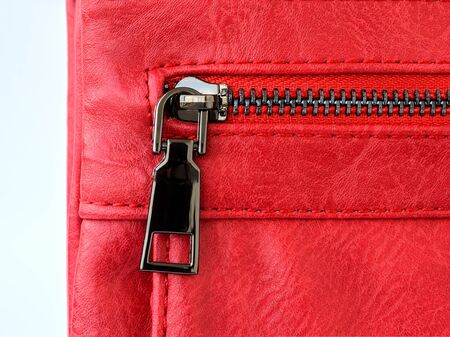 Zip pocket of a small red casual handbag. Fashionable modern accessories made of artificial or genuine leather. Close-up.の写真素材
