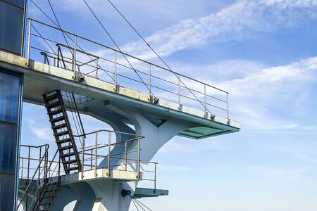 Multilevel sport diving board in the outdoor pool swimming on a background of blue summer sky with...