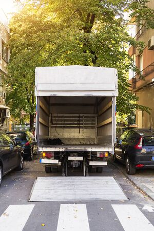 Open furniture delivery truck on a city street. Empty moving van with rear doors opened. On an autumn sunny day. Back view.の写真素材