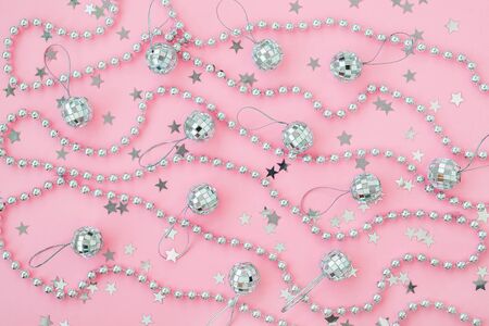 Christmas mirror balls and bead garland on a pastel pink background with silver stars. Festive flat lay for Christmas and New Year greeting card. Top view.の写真素材