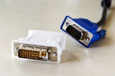 Dvi-d socket of white adapter for blue vga socket monitor cord behind it. Connection of computer devices with plugs of different types. Close-up.の写真素材