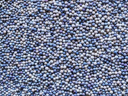 A lot of tiny ceramic balls or granules in color range from beige to dark blue as a background....
