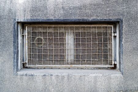 Rectangular basement or cellar window is tightened with wire metal mesh and grille. Technical floor...