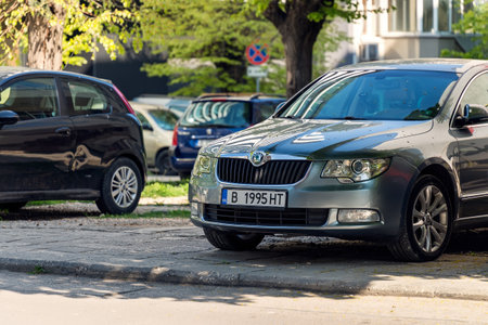 Varna, Bulgaria, April 28, 2020. Small plant parts on the windshield and hood of Skoda parked by a tree near multi-storey apartment building on a sunny spring day.のeditorial素材