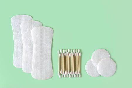 Few disposable panty liners, cotton pads and cotton buds wood stick on a pastel mint background. Flat lay of feminine hygiene items. Copy space. Top view.の写真素材