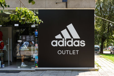 Varna, Bulgaria, July 01, 2020. Entrance to Adidas outlet shop from a city street on a sunny summer day. Signboard of Adidas logo brend sign on store, boutique. Top quality sportswear.のeditorial素材