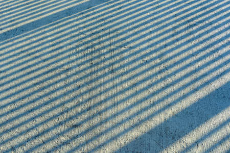 Gap step diagonal shadows from sunlight on a scratched concrete surface on a sunny day. Ascending...