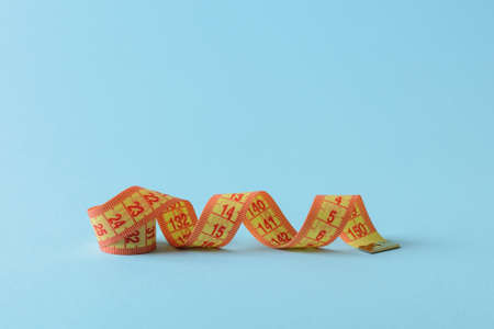 Yellow measuring tape curles on a blue medical background. Concept of healthy eating, body weight...