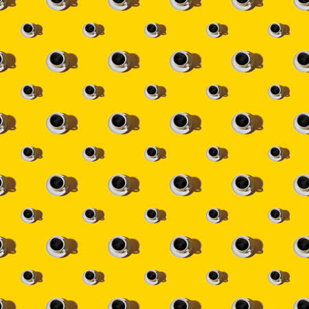 Seamless pattern of large and small cup of hot coffe on white saucer over a bright yellow...