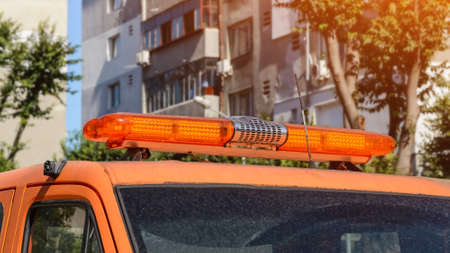 Orange warning lightbar on a stationary car tow track parked on a city street on a summer sunny day. Roof mounted lightbar on a automotive technical assistance vehicle. Close-up.の写真素材
