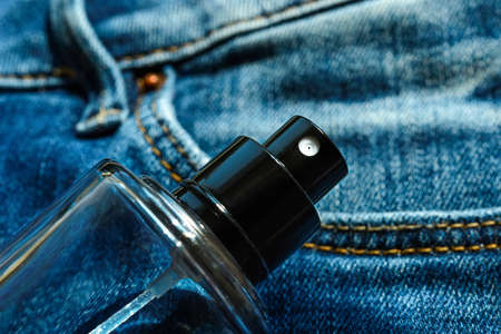 Glass bottle of unisex fragrant perfume or scented toilet water on a blue denim. Casual light scent for everyone. Top view.の写真素材