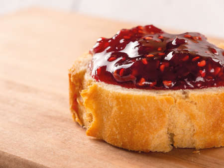 Close-up of delicious sandwich with raspberry jam on a wood cutting board. Traditional homemade red...