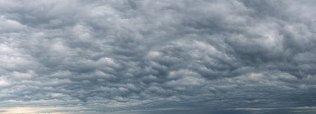 Low gray stratocumulus clouds covered the whole sky. Dark overcast sky panorama. Wide image of...