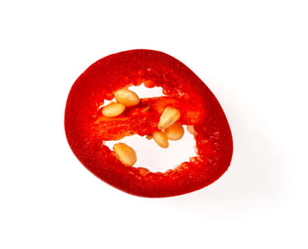 Fresh slice of red hot chili pepper isolated on a white background. High quality macro of capsicum annuum ornamental pepper single slice. Raw spicy seasoning for meat, fish, vegetables. Top view.の写真素材
