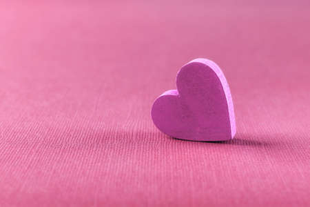 Pink valentine heart against textured pink background with copy space. Macro. Mockup design element for Valentine day holiday, greeting card and banner. Symbol of love, passion, tenderness.の写真素材