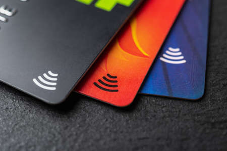Three credit cards with contactless pay technology on a black background macro. Debit cards for...