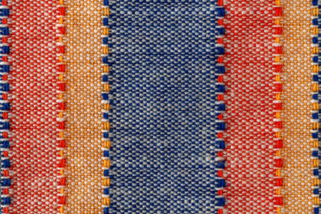 Macro texture of plain weave fabric. Striped cloth background of red, blue, orange and white colors....