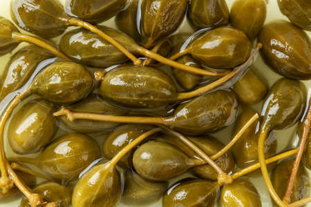 Pickled caper berries as a background. Marinated fruits of caper bush. Mediterranean cuisine...
