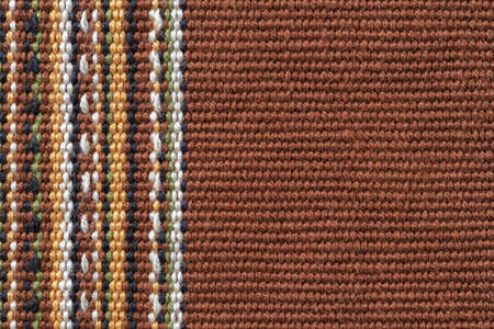 Brown textile background with copy space. Plain weave fabric with vertical stripes of white, yellow, green and black colors. Colorful woven fabric texture for design element. Weft and warp. Front view.の写真素材