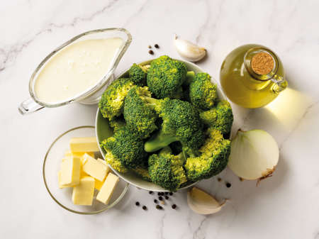 Raw ingredients for cooking cream of broccoli soup: broccoli florets, cream, butter, garlic, onion and olive oil. Puree soup of broccoli recipe. Tasty vegetarian food concept. Top view.の写真素材