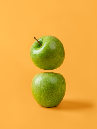 Two fresh green apples against yellow background. Organic ingredient for weight loss slimming diet. Raw juicy fruit for vitamin healthy eating. Antioxidant vegetarian snack. Front view.の写真素材
