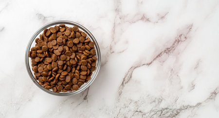 Dry pet food in a glass bowl over marble background. Glass feeding bowl full of gluten free dry...