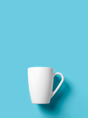 White cup over blue background. Empty mug against turquoise surface. Large cup mockup for breakfast design. Crockery for hot beverages. Modern tableware concept. Copy space. Front view.の写真素材