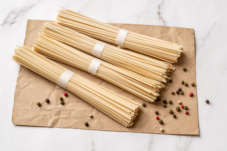 Dried udon nudles and spice prepared for cooking. Four bunches of raw asian vegan pasta from wheat...