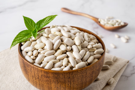 Close-up of white kidney beans in a wooden bowl. Bowl of raw dry white beans prepared for cooking baked beans, bean soup or pie. Plant protein, harvesting concept. Front view.の写真素材