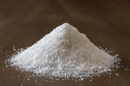 Heap of monosodium glutamate over brown background. Pile of MSG white crystals front view. Common food additive, flavor enhancer, E621 concept. Close-up.の写真素材