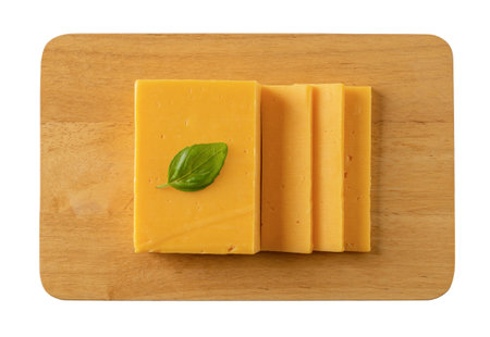 Sheddar cheese slices on a cutting board cutout. Whole and slaced cheese on a wooden chopping board isolated on a white background. Dairy product concept. Top view.の写真素材