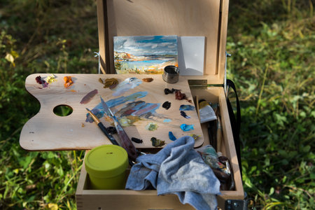 Wooden easel with watercolors and brushes in nature.の写真素材