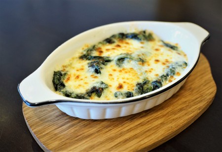 a bowl of Baked spinach with cheese on wooden plate.の写真素材