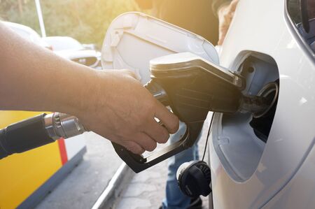 A man pumping gasoline fuel in to car tank inlet at gas station