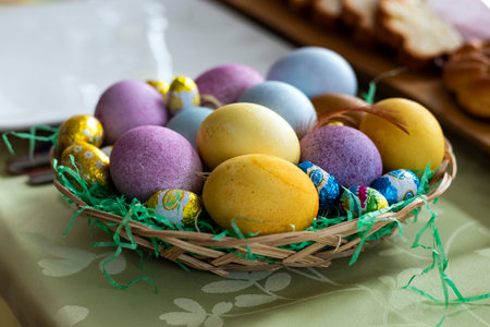Colorful Easter eggs in a basket on a green tablecloth.