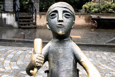 Close-up of a whimsical bronze statue of a child holding a scroll in Tbilisiâ€™s old town....