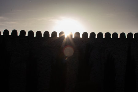 Sunset light beams through the silhouette of an ancient stone fortress wall in Mtskheta, Georgia. A...