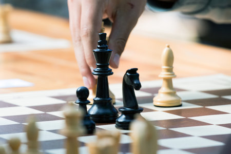 Close up of hand of businessman playing chess game. Business strategy concept.