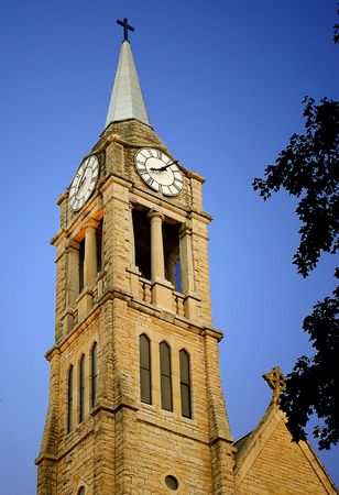 Late afternoon sunlight warms the limestone steeple of St. Denis Catholic church in Lockport, IL, USAの写真素材