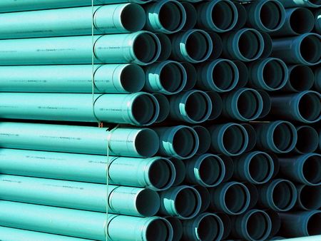 PVC plastic pipes stacked at the construction site ready to be laid as a sewer line.  Interesting contrast between highlights and shadows produces patterns of straight lines and circular end view.の写真素材