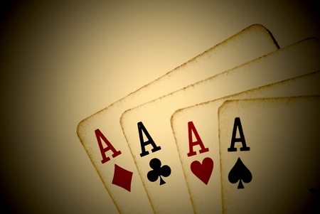 Four aces from an old worn deck of playing cards. Sepia tone and vignette effect.