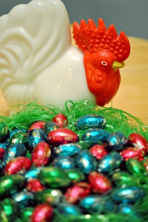 Candy easter eggs in a nest guarded by a hen figurine 