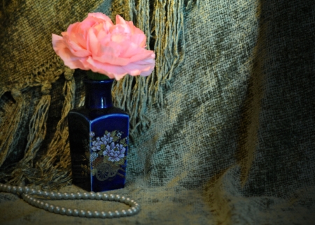 Single carnation flower in a tiny oriental style vase with a string of pearls on a draped fabric background の写真素材