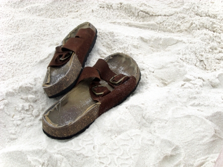 Well-worn pair of sandals in the white beach sand の写真素材