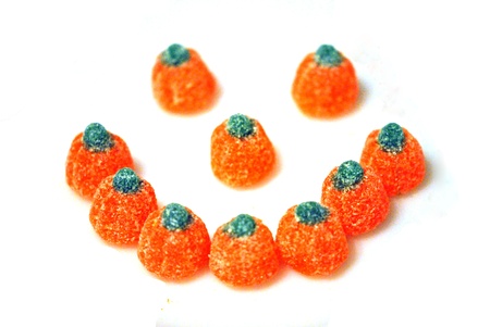 Halloween pumpkin candies arranged in a smiley face, isolated on white 