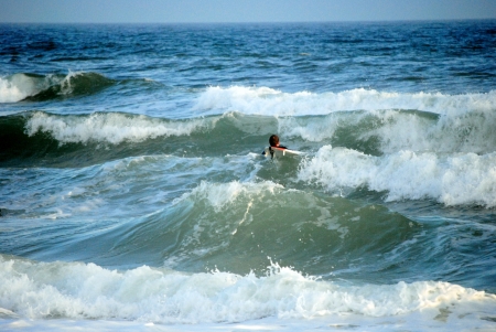 Surfer heads out to catch a wave in the blue-green waters of the Gulf of Mexico の写真素材