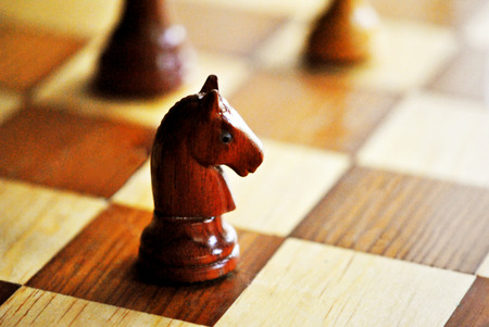Carved chess pieces and board; featuring black knight の写真素材