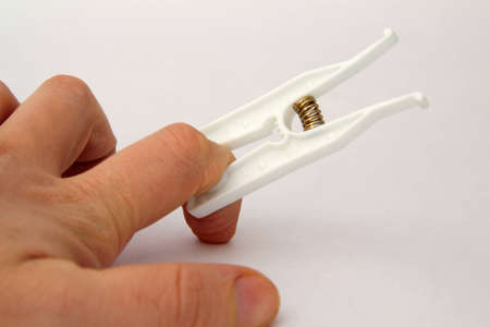 hand, a finger and a clothespin on a white backgroundの写真素材