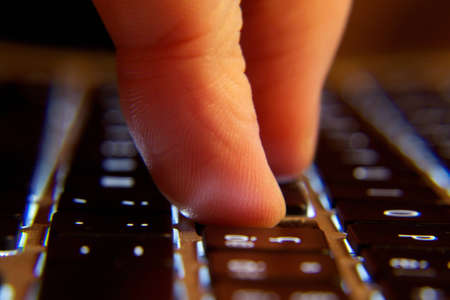 a finger pressing a key on the keyboard illuminatedの写真素材