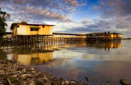 Reflection of native houses on water and the sky at Kampung Danga, Johore, Malaysia の写真素材